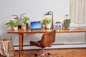 Image of a brown desk and chair featuring LED tabletop Grow Lights, lighting houseplants on the desk